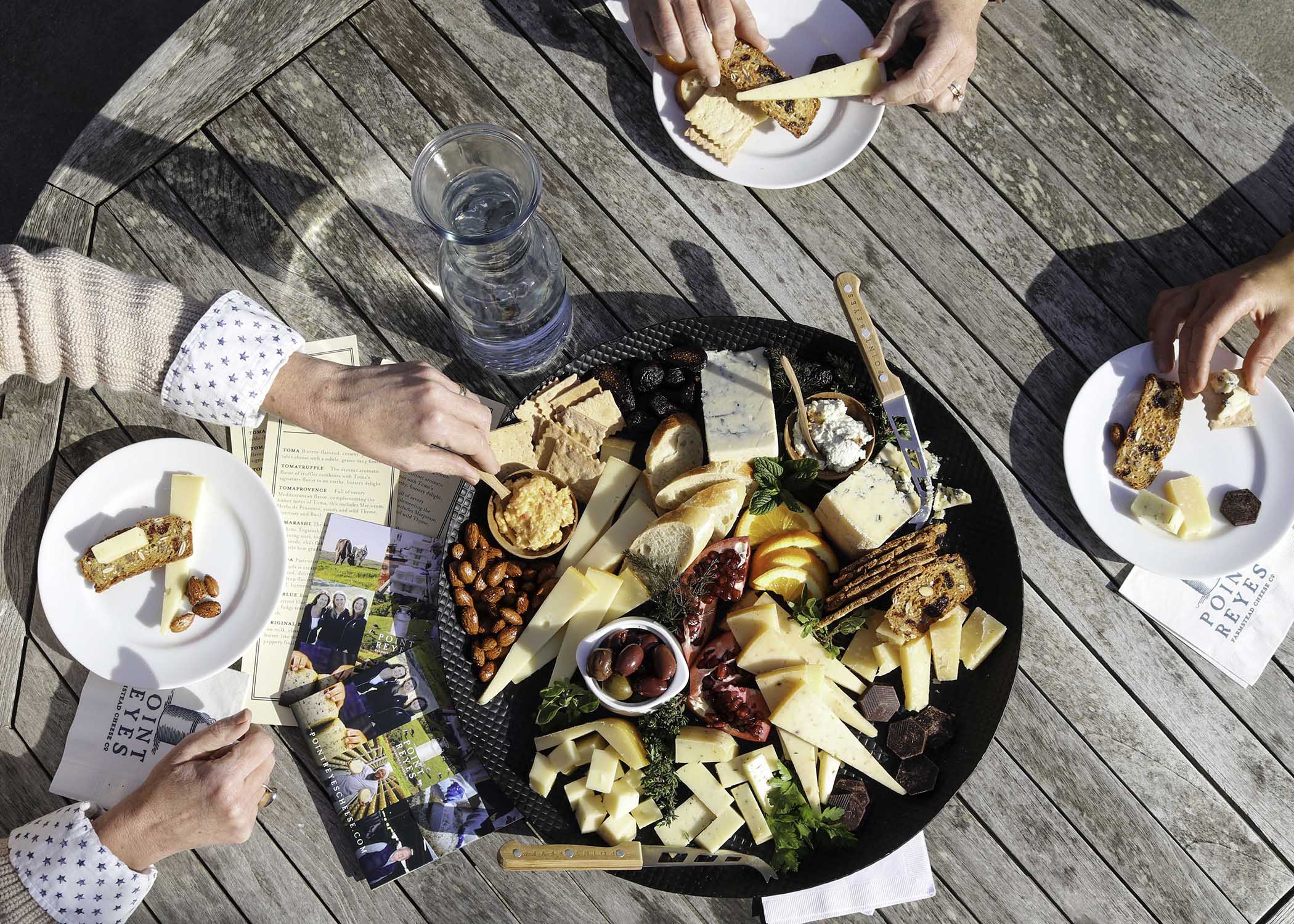 Hands reaching for a cheeseboard