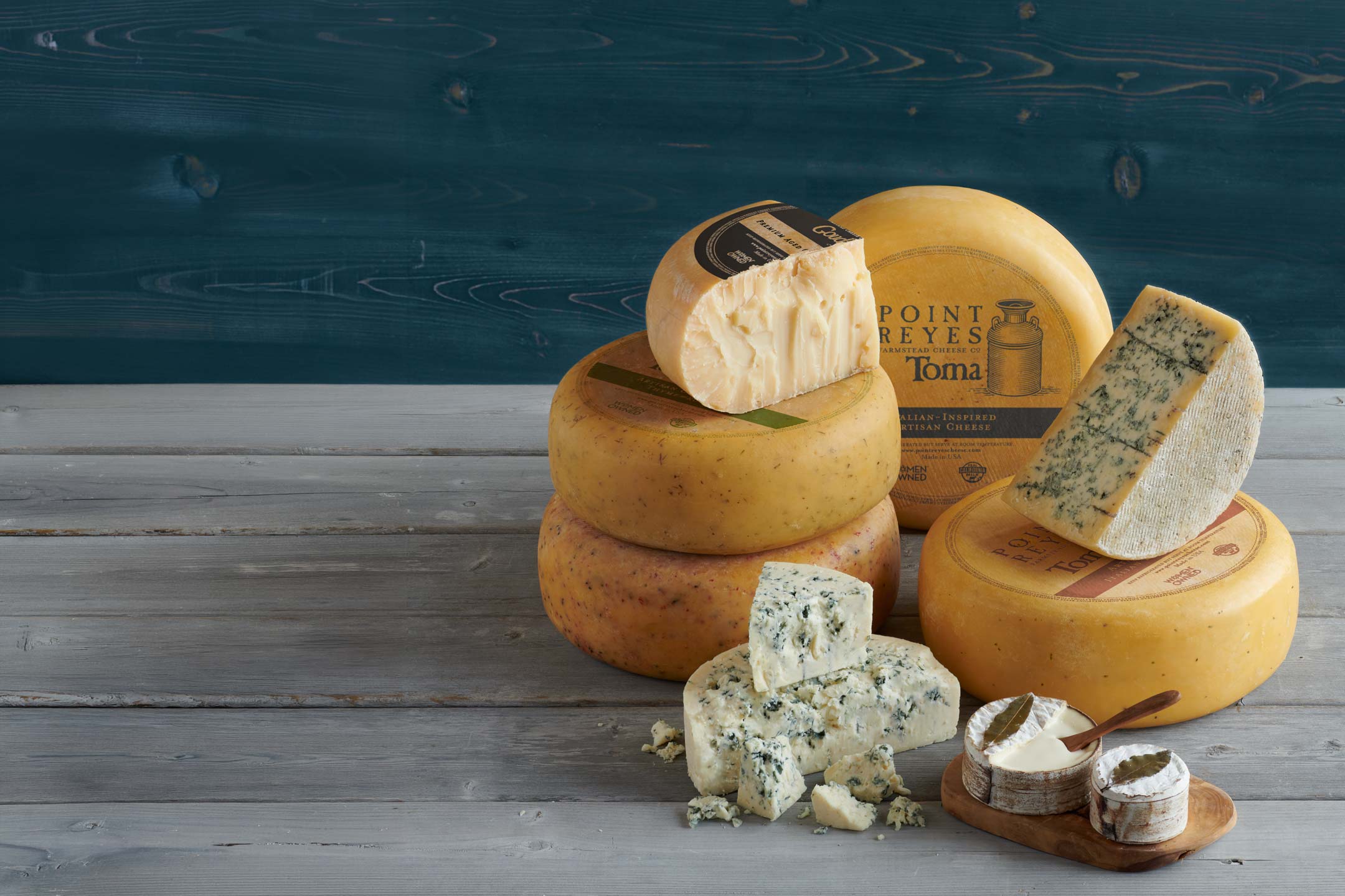 Assorted cheeses on a wooden surface with a blue watercolor background