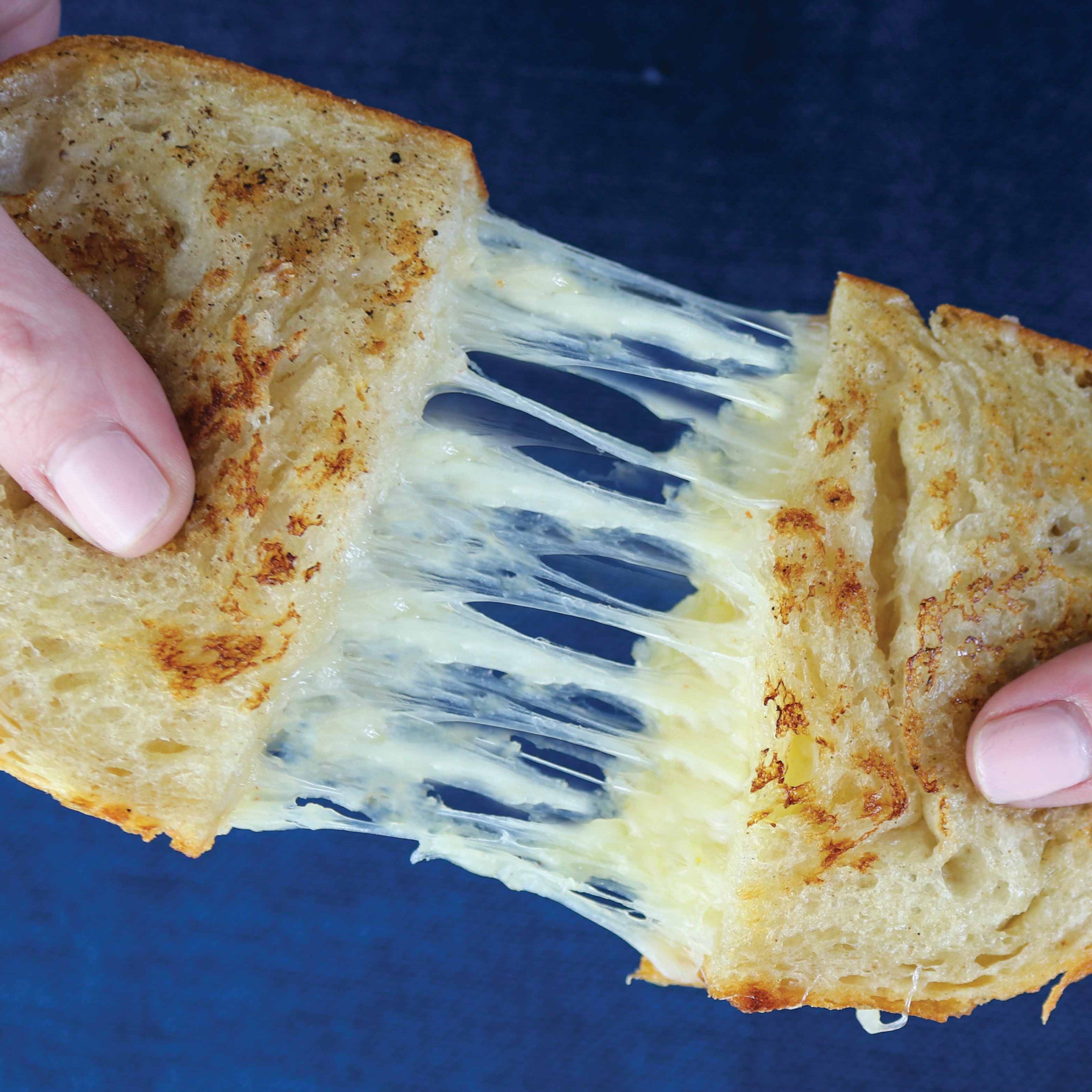 A grilled cheese sandwich being pulled apart