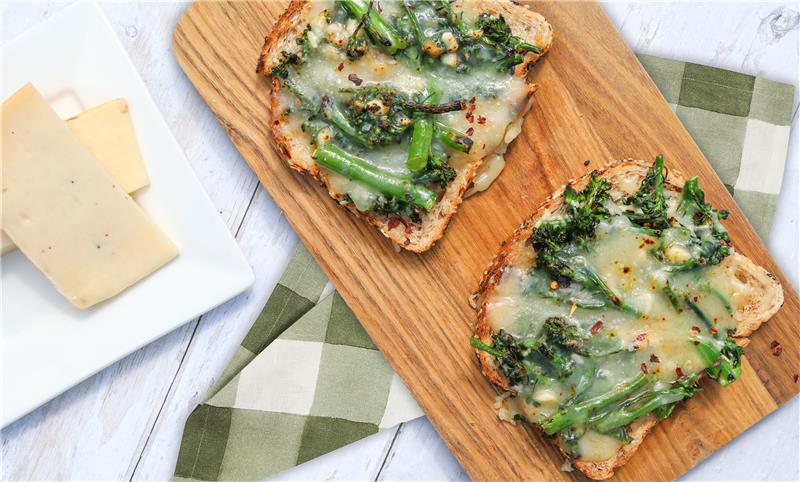 Open faced cheese melt with broccolini on a board