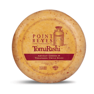 Point Reyes TomaRashi cheese wheel on a white background