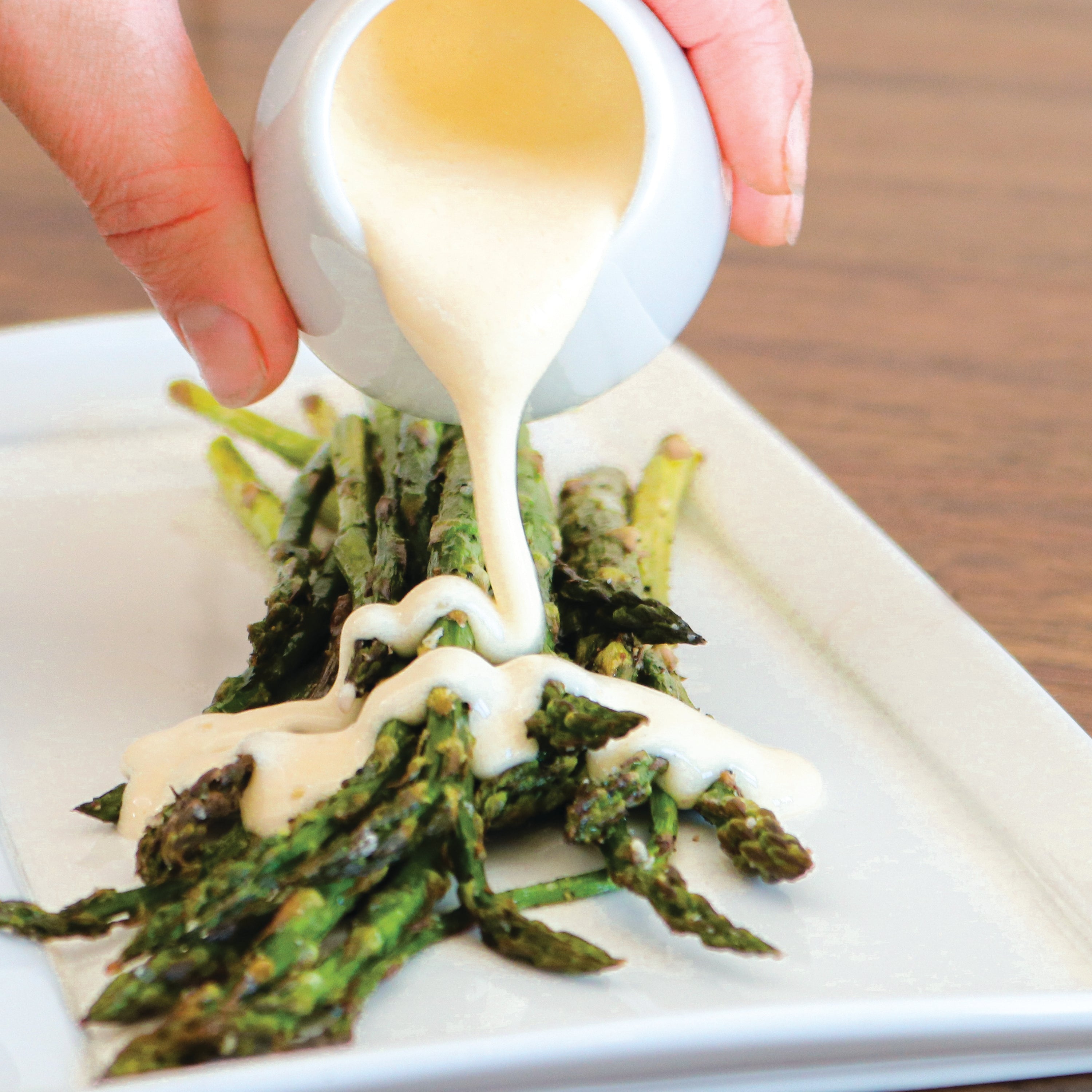 Roasted asparagus with TomaTruffle fonduta sauce being drizzled on top