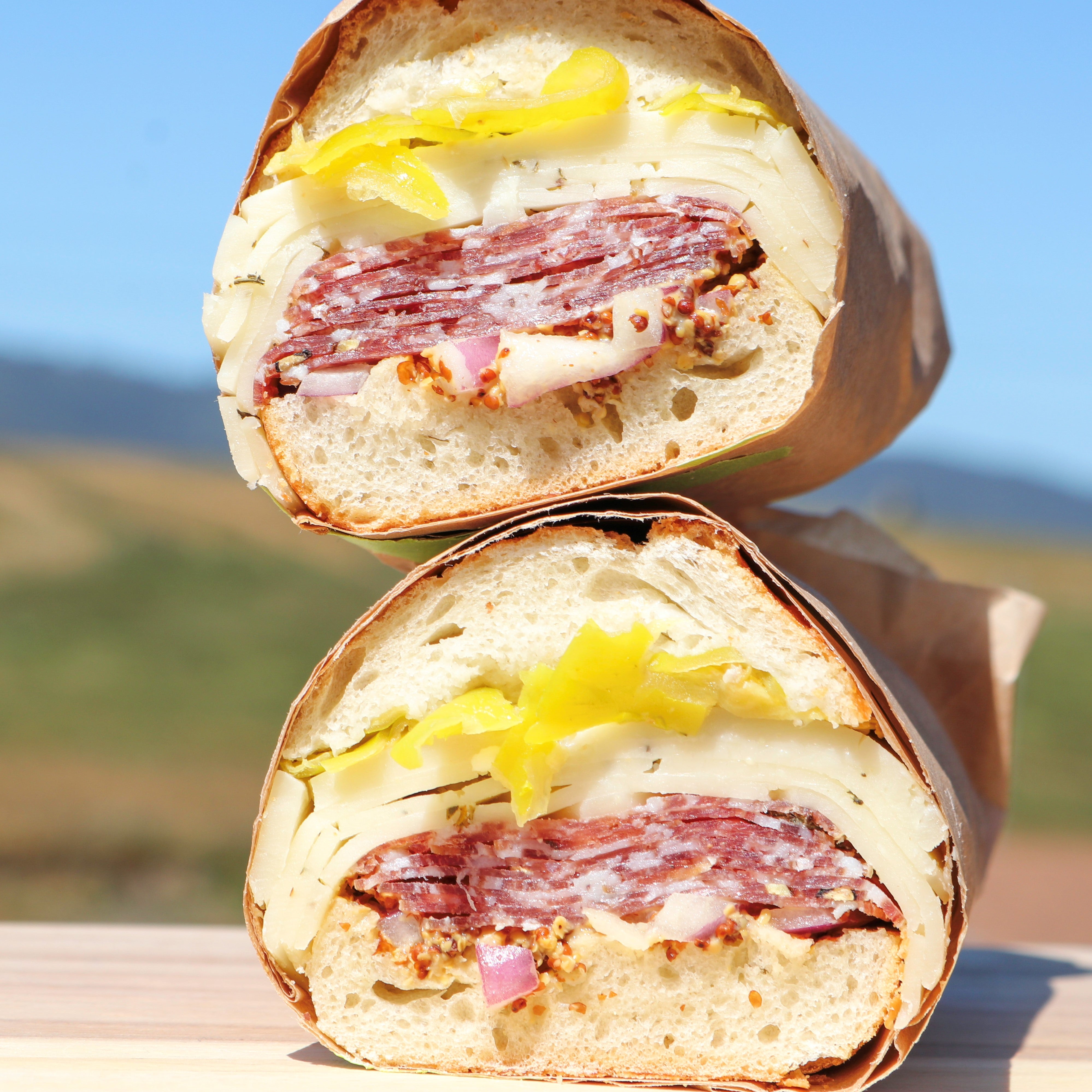 A sandwich on a baguette made with TomaProvence cheese, grainy mustard, salami, and pepperoncini's 